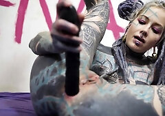 Fully inked blonde stretches her ass with black toy